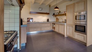 Eine moderne Küche mit Gasherd, Holzschränken und einem eingebauten Backofen.