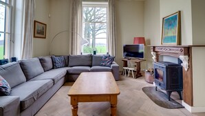 Ein gemütliches Wohnzimmer mit einer Eckcouch, einem Holztisch, einem Kamin und einem Fernseher.