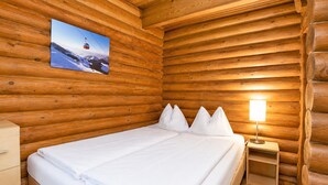 A wooden cabin room with a bed, pillows, a nightstand, and a lamp. - Rustic Chalet Near Skiwelt Wilder Kaiser (Woergl)