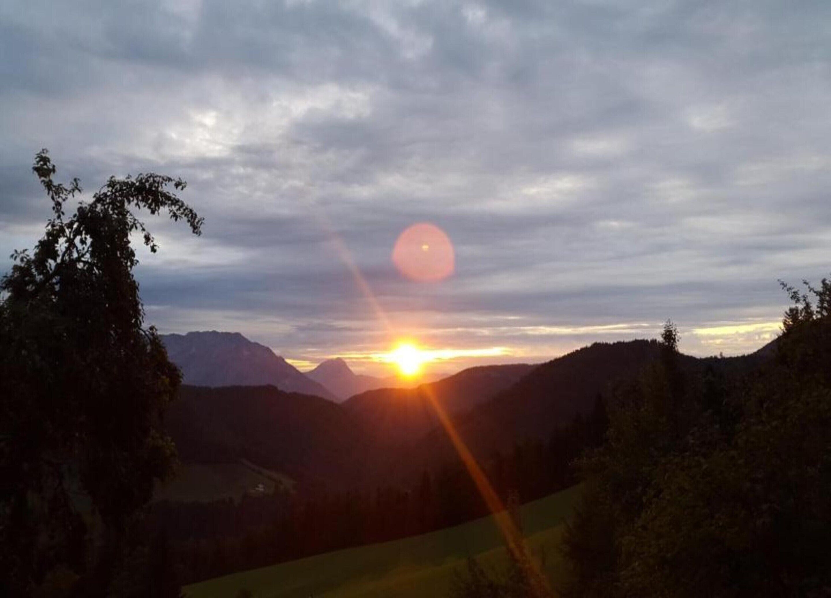 A sunset over a mountainous landscape with a clear sky.
