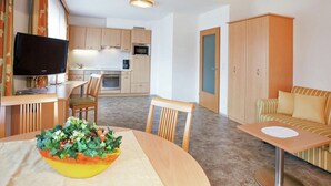 Une chambre d’hôtel moderne dotée d’un coin repas, d’une kitchenette et d’un téléviseur.