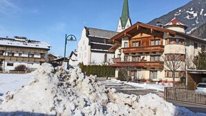 Un hôtel de style alpin traditionnel, caractérisé par un clocher d’église imposant et un grand monticule enneigé au premier plan.