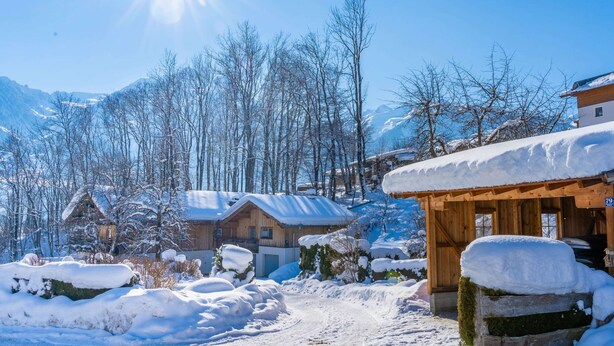 A snowy village with wooden buildings, a clear sky, and mountains in the background. - Apartment With Mountain View (Piesendorf)