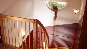 A wooden staircase with a handrail, a window with a view of greenery, and a wall-mounted light fixture. - Chalet in Furth Near Zell am See Ski Slopes (Piesendorf)