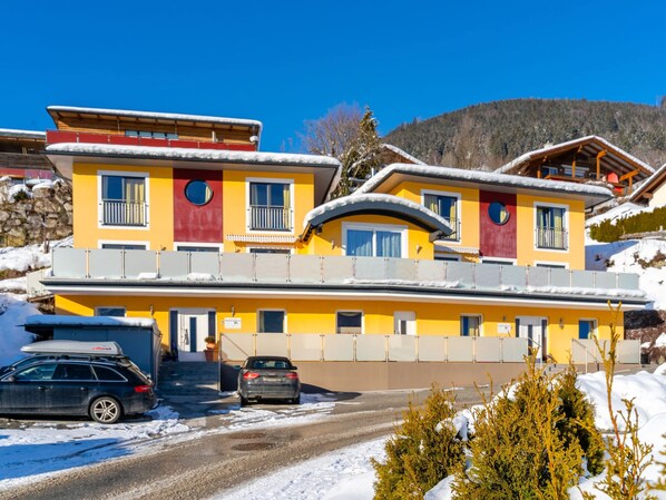 A multi-story hotel with a yellow facade, balconies, and a ski slope in the background. - Chalet in Furth Near Zell am See Ski Slopes (Piesendorf)