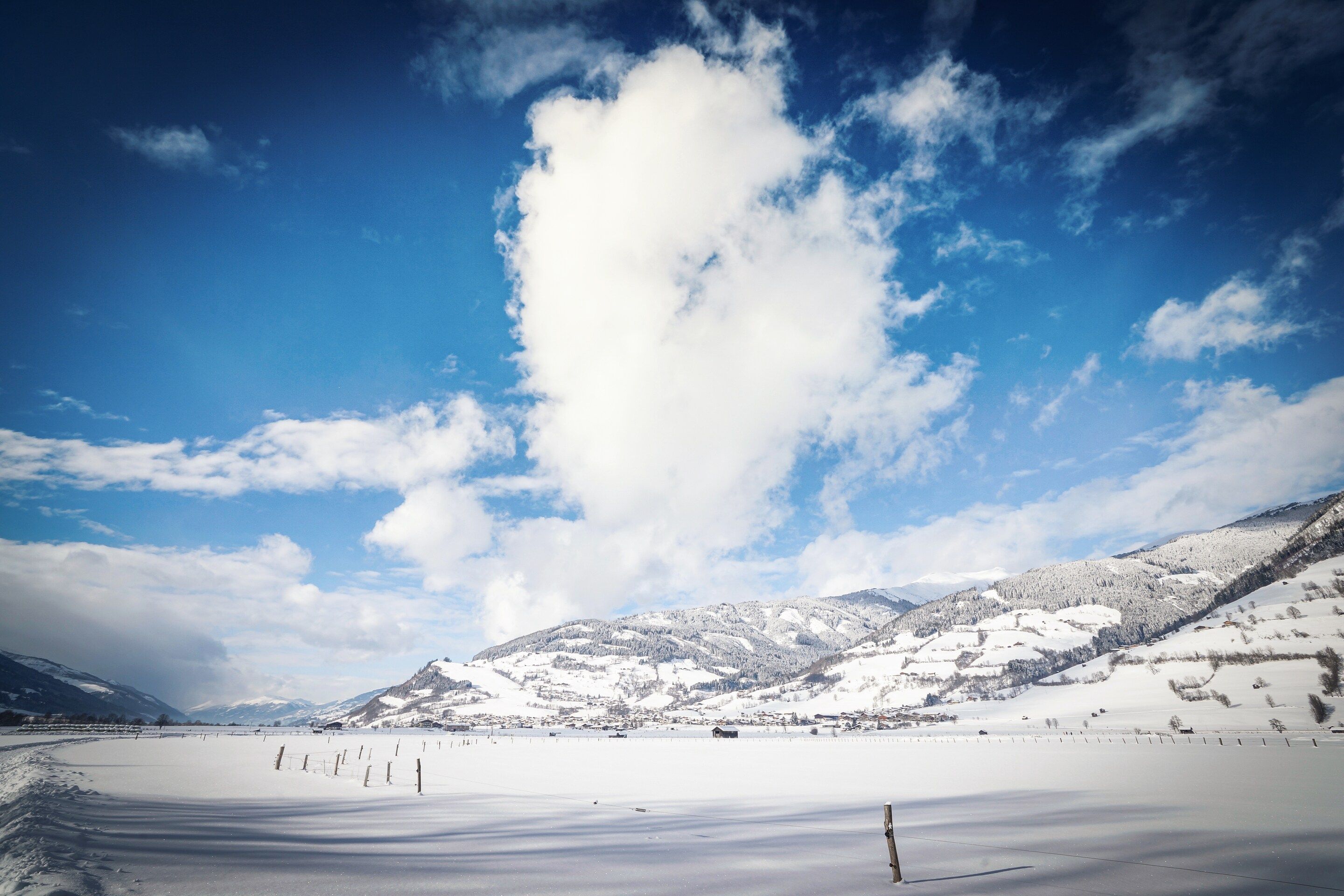 A snow-covered landscape with a clear sky and a mountain in the background.