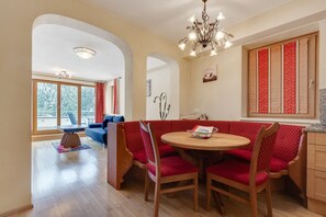 A dining area with a round table, red upholstered chairs, and a chandelier. - Chalet in Saalbach Near Ski Lift (Saalbach-Hinterglemm)