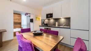 Una cocina moderna con una mesa de comedor de madera, sillas moradas y un microondas sobre la encimera.