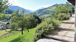 Een prachtig uitzicht vanaf een balkon over een weelderig dal met bomen en verre bergen.
