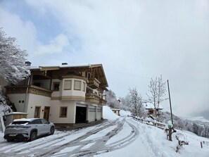 Une maison à deux étages avec un garage, un balcon et une allée recouverte de neige.