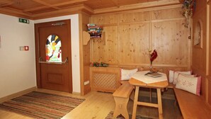 A wooden interior with a bench, a table, a shelf with books, and a door with a stained glass window. - Apartment in Kaltenbach Near Ski Lift (Stumm)