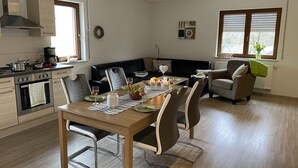 Moderni keittiö, jossa on ruokailutila, sohva ja ikkuna, jossa on sälekaihtimet.