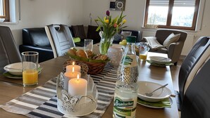 Ruokapöytä, jonka päällä on kynttilöitä, vesipullo ja hedelmäkori.