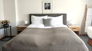 A neatly arranged hotel room with a large bed, a bedside table, a nightstand, a framed picture on the wall, and a small potted plant. - Cozy Chalet in Bramberg am Wildkogel with Sauna near Ski Lift (Bramberg am Wildkogel)