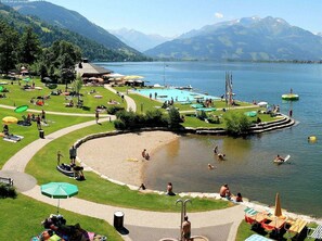 A lakeside resort with a swimming pool, sun loungers, and a grassy area. - Luxury Chalet near Ski Area in Zell am See (Zell am See)