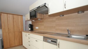 A modern kitchen with wooden cabinets, a stainless steel sink, and a built-in oven.