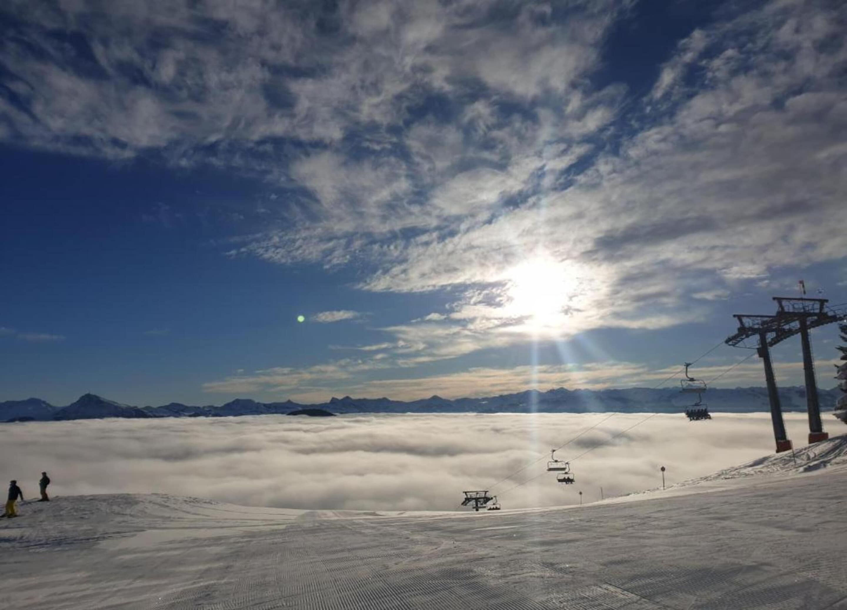 A ski slope with a ski lift and a mountain range in the background.