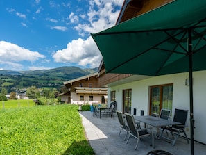 Un bâtiment doté d’un patio comprenant un espace extérieur avec des sièges et un parasol vert.
