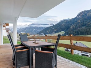 A covered outdoor seating area with wicker chairs and a table, overlooking a mountainous landscape. - Apartment Near the Zillertal Arena ski Area (Wald im Pinzgau)