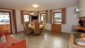 Una habitación acogedora con una mesa de comedor, sillas, un sofá, un televisor y una zona de cocina con un fregadero y armarios.