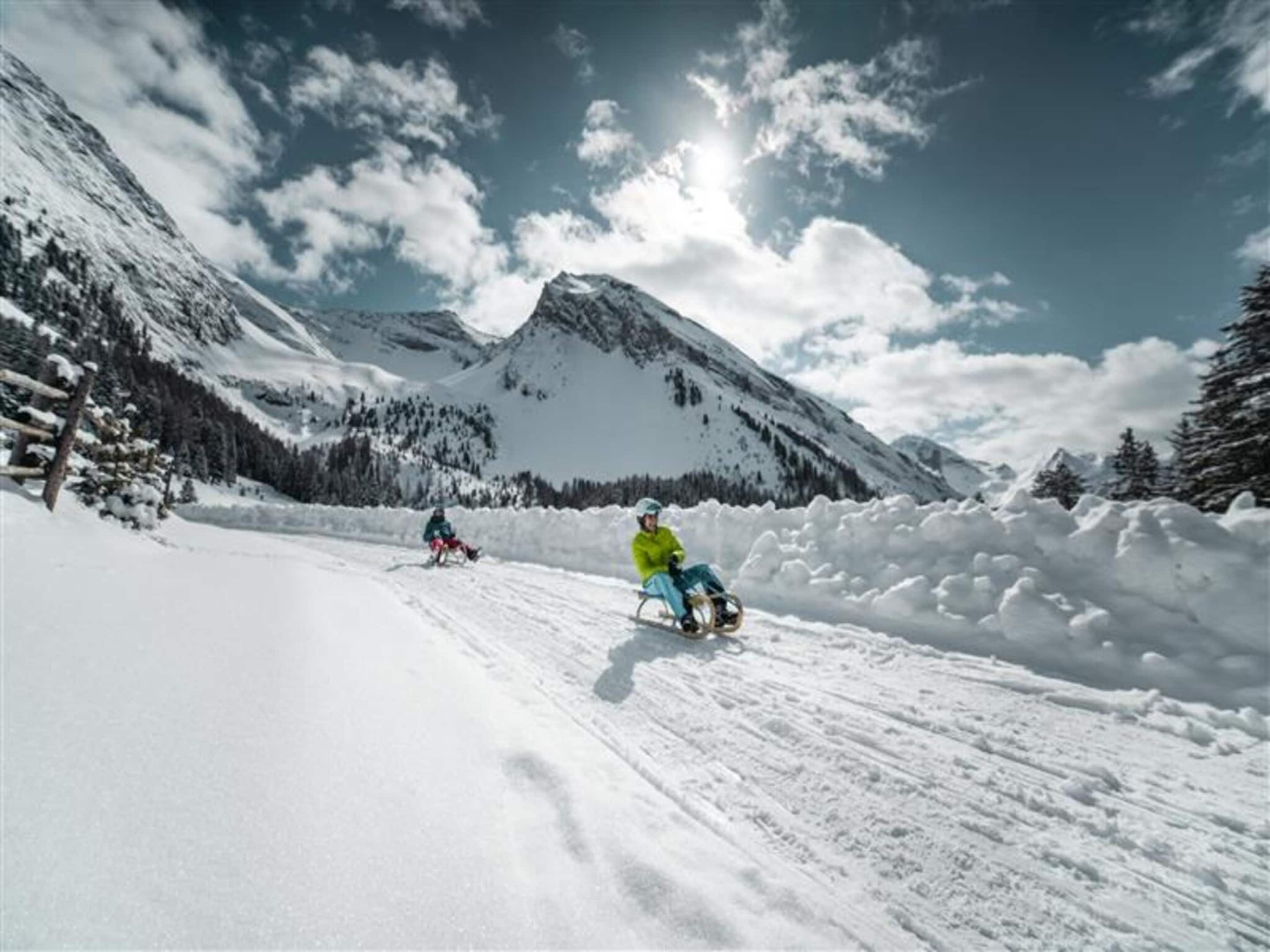 A snowy mountain landscape with two people on snowboards.