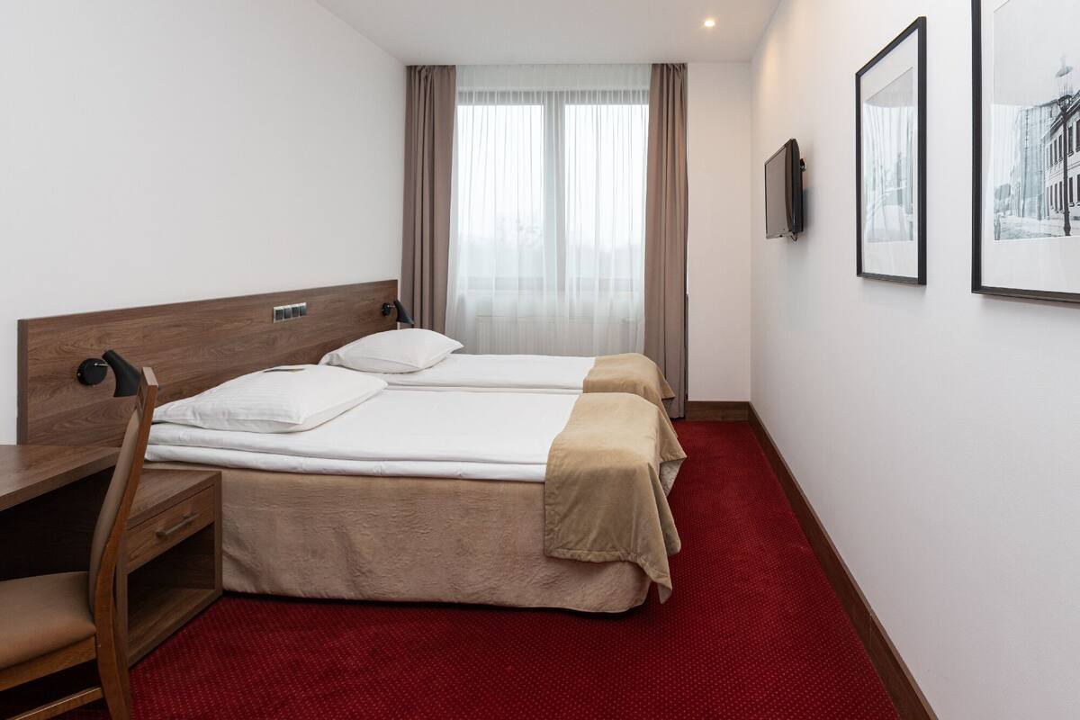 A hotel room with two beds, a desk, and a chair.