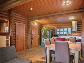 A log cabin interior with a dining area, wooden walls, and a kitchen with red cabinets. - Chalet in Worgl Near Ski Bus Stop (Woergl)