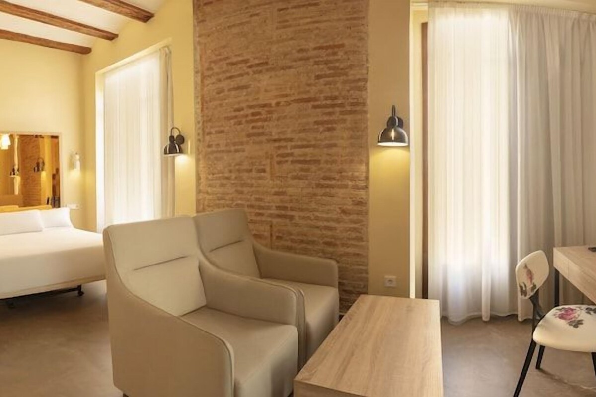 Una habitación de hotel con cama, escritorio, silla, televisor y baño.