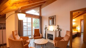 A cozy room with a fireplace, wooden beams, and large windows. - Luxury Apartment in Brixen (Brixen im Thale)