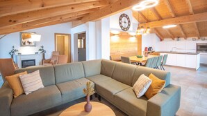A modern living room with a sectional sofa, a dining area, and a kitchen. - Luxury Apartment in Brixen (Brixen im Thale)