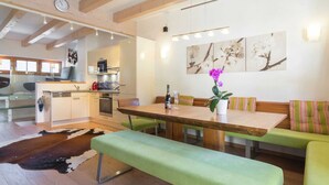 Eine moderne Küche mit Holzbalken, einem Essbereich mit einer Bank und einem Wohnbereich mit einer Couch und Kunstwerken.