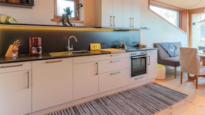 A modern kitchen with a central island, built-in oven, and a window above the sink. - Elite Chalet near Ski Slopes in Westendorf (Westendorf)