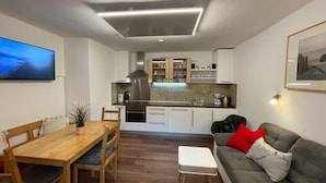 Une cuisine moderne avec des armoires blanches, une hotte de cuisinière en acier inoxydable et un four encastré.