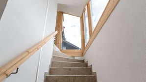 Un escalier avec des rampes en bois et une lucarne donnant sur l’étage supérieur.