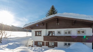 Ein Chalet mit geneigtem Dach, Holzfassade und zahlreichen Fenstern.