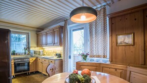 A kitchen with wooden cabinets, a round dining table, and a hanging light fixture.