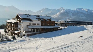 Ein schneebedecktes Bergresort mit einem Holzhaus, Skipisten und einer Brücke.