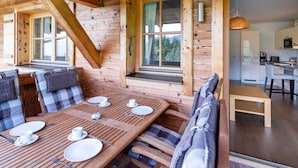 Eine Holzhütte mit Essbereich, Küche und Blick ins Freie.