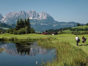 Un parcours de golf avec un étang, des arbres et une montagne en arrière-plan.