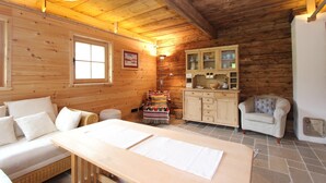 A cozy wooden cabin interior with a sofa, a dining table, a cabinet, and a chair. - Cozy Chalet in Sankt Johann in Tirol near Ski Area (Sankt Johann in Tirol)