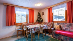 Un coin repas chaleureux avec une table dressée pour quatre personnes, un canapé et un sapin de Noël.