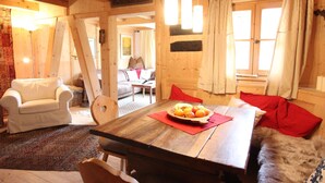 A cozy wooden interior with a dining table, chairs, a sofa, and a red cushion. - Chalet in St Johann on Ski Slopes (Sankt Johann in Tirol)