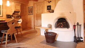 A rustic wooden interior with a stone fireplace, wooden furniture, and a basket on the floor. - Chalet in St Johann on Ski Slopes (Sankt Johann in Tirol)