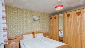 A bedroom with a wooden bed, a nightstand, a wardrobe, and a ceiling light. - Villa in Piller Near Ski Bus & Lake (Fliess)