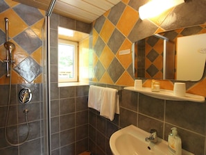 A bathroom with a shower, sink, and a window.