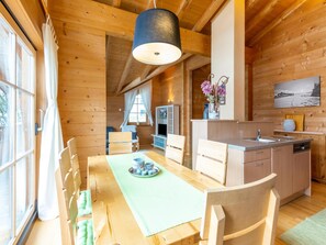 A wooden cabin interior with a dining area, kitchen, and a large window. - Penthouse With Steam Bath (Brixen im Thale)