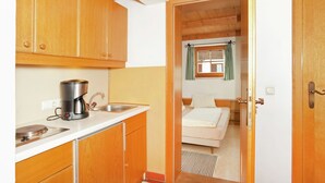 A compact kitchen with wooden cabinets, a coffee maker, and a sink. - Apartment in St. Johann in Tyrol With a Garden (Sankt Johann in Tirol)