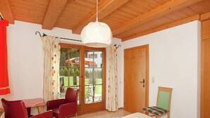 A room with a bed, a table with chairs, a wooden ceiling, and a door. - Apartment in St. Johann in Tyrol With a Garden (Sankt Johann in Tirol)