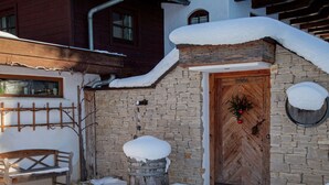 A stone building with a wooden door, snow on the roof, and a bench outside. - Apartment in St. Johann in Tyrol With a Garden (Sankt Johann in Tirol)