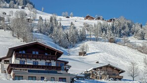 A snow-covered mountain resort with wooden buildings, ski slopes, and a clear blue sky. - Apartment Brixen Near Ski Lift (Brixen im Thale)